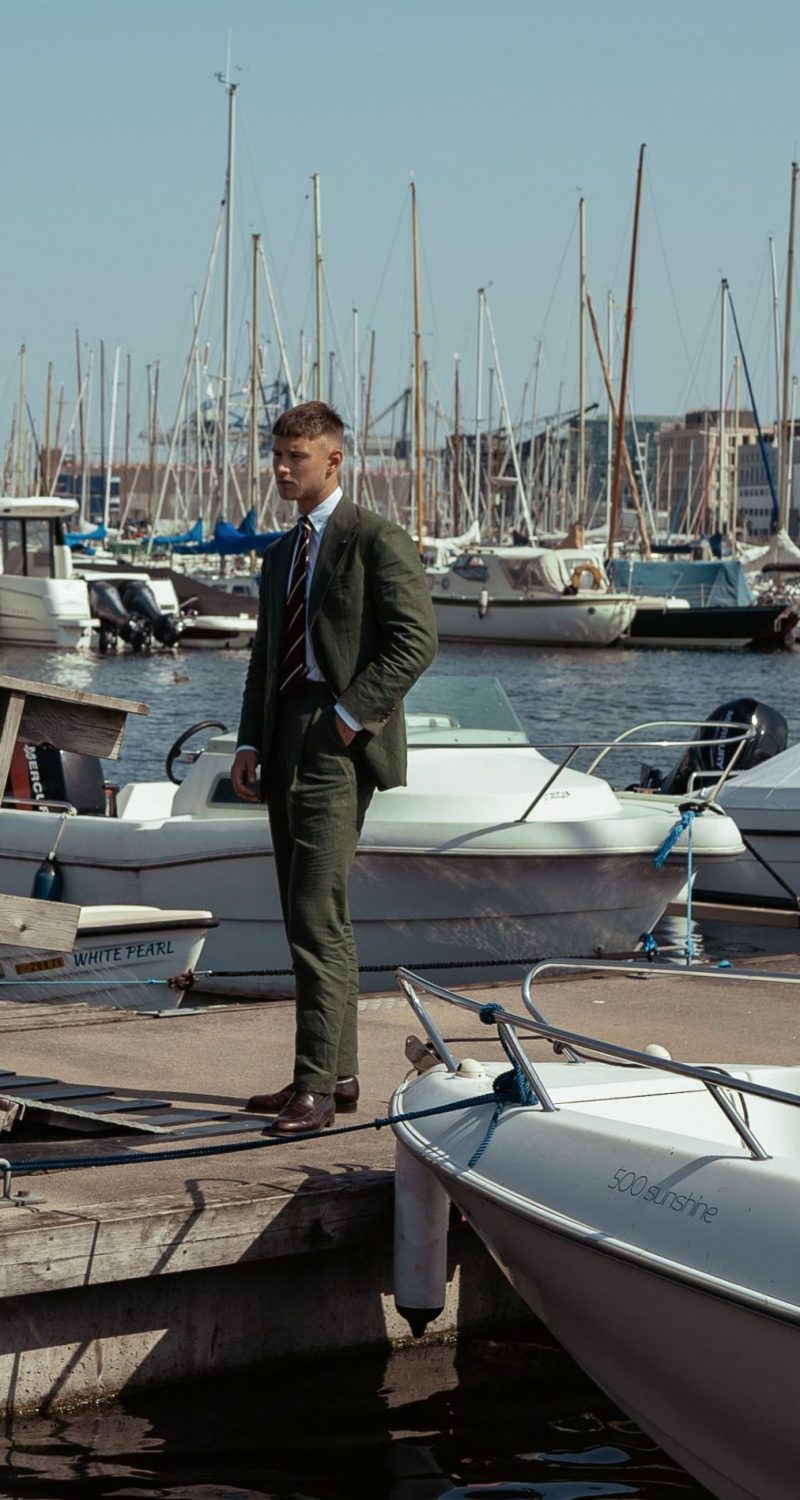 green linen suit for a summer wedding, model standing on a dock