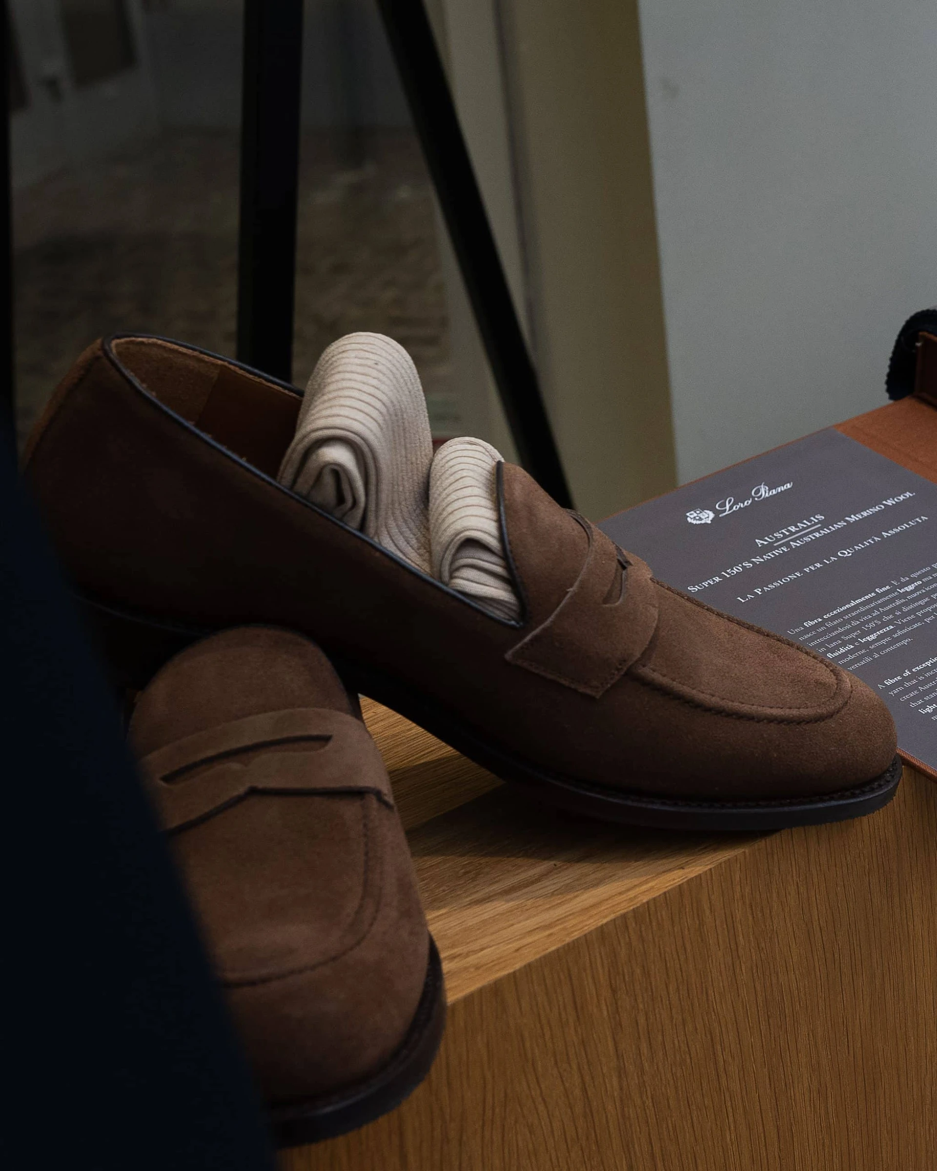 Brown suede loafers by Mond, with a pair of rifled beige socks rolled up into one of them